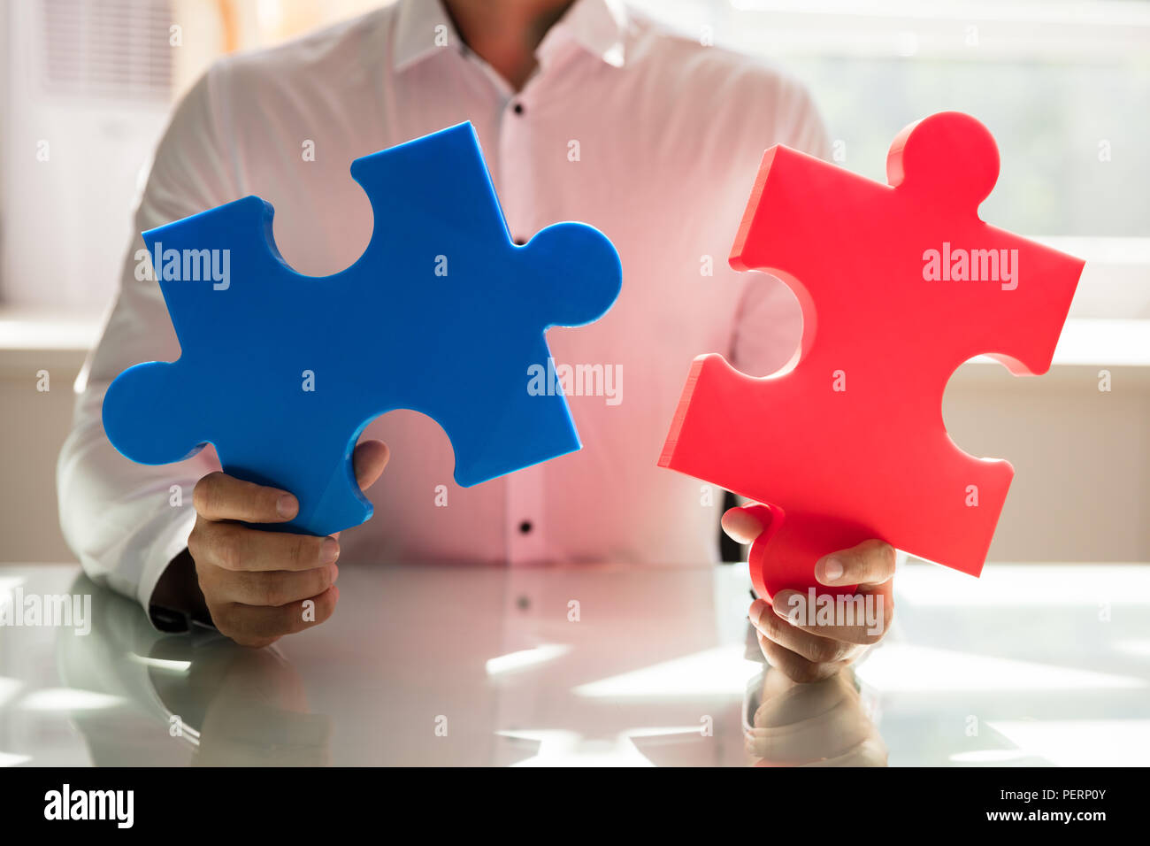 Der Geschäftsmann Hand verbinden zwei farbenfrohe Puzzles im Büro Stockfoto