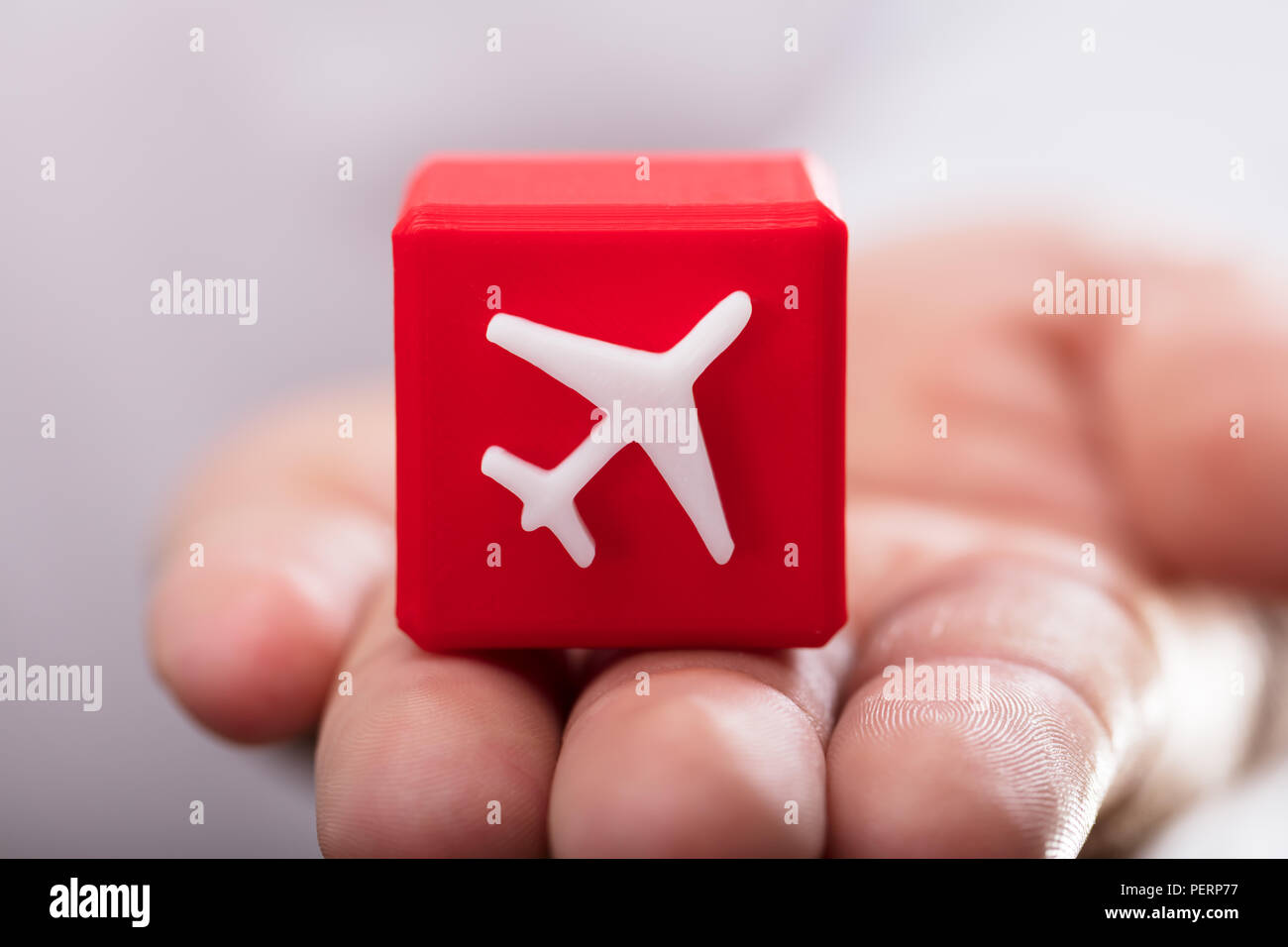 Nahaufnahme einer Hand halten roten kubische Block mit dem Flugzeug Symbol Stockfoto