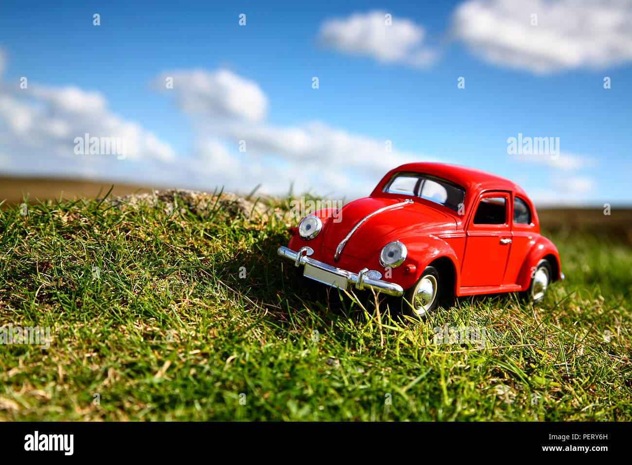 Red toy Volkswagen Beetle Auto auf Grünland in der Landschaft Travel Concept geparkt Stockfoto