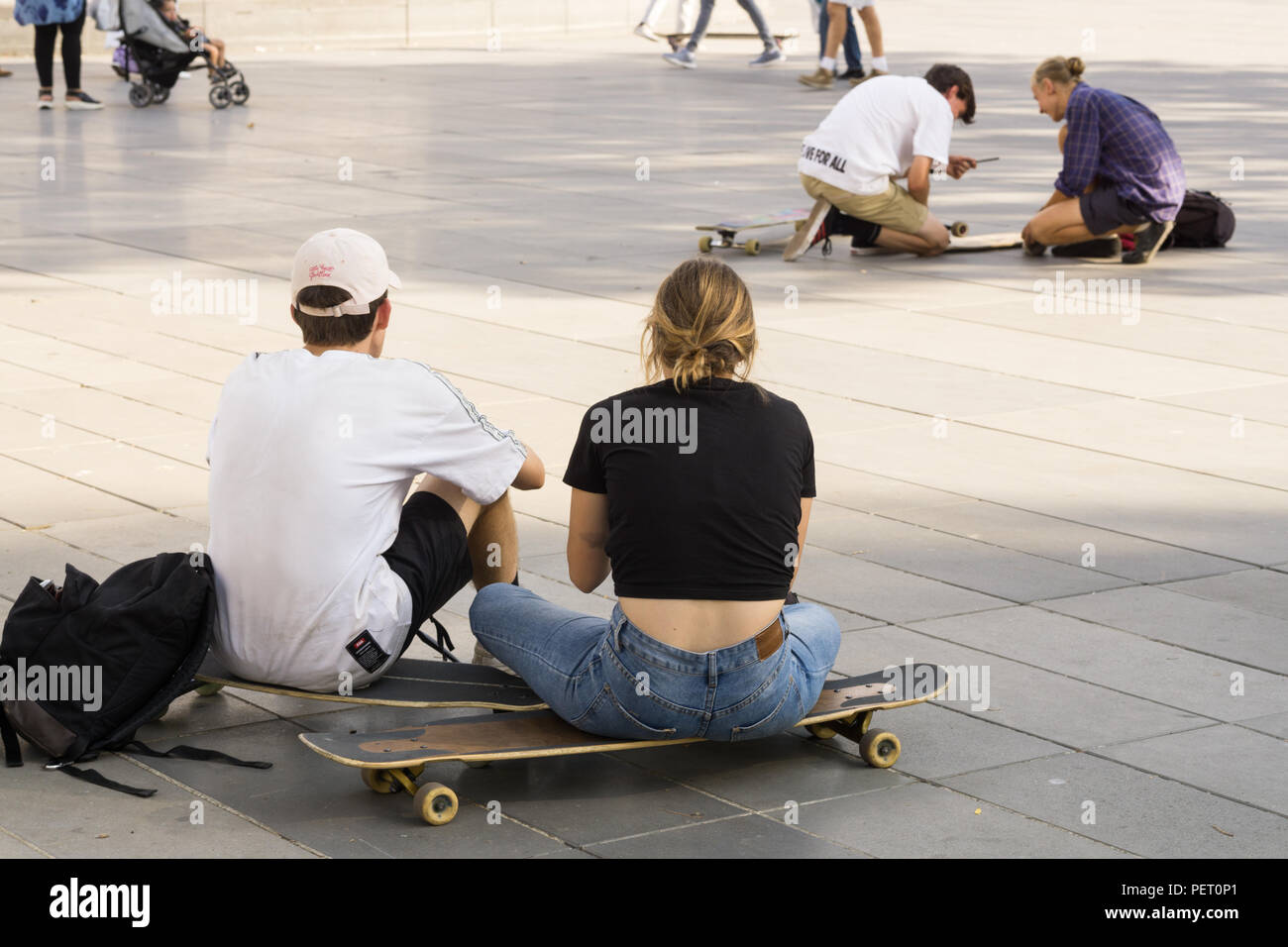 Paris Skateboarder - Junge und Mädchen Skater auf ihren Skateboards sitzend, von hinten an der Place de la Republique in Paris, Frankreich, Europa gesehen. Stockfoto