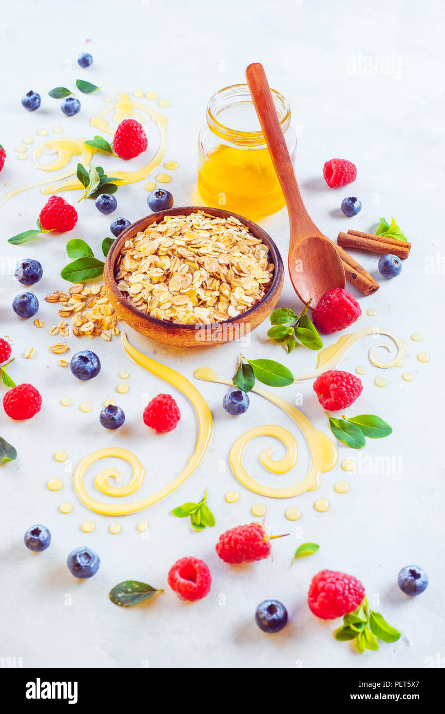 Haferflocken porridge Zutaten auf einem weißen Holz- Hintergrund. Müsli, Honig, Zimt, Beeren und mit Kopie Raum Stockfoto