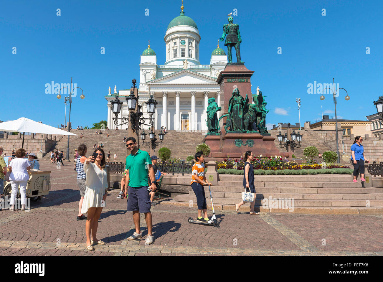 Finnland Tourismus Sommer, Blick auf eine touristische Paar in Helsinki für eine selfie Foto vor der lutherischen Kathedrale und Alexander Denkmal posieren. Stockfoto