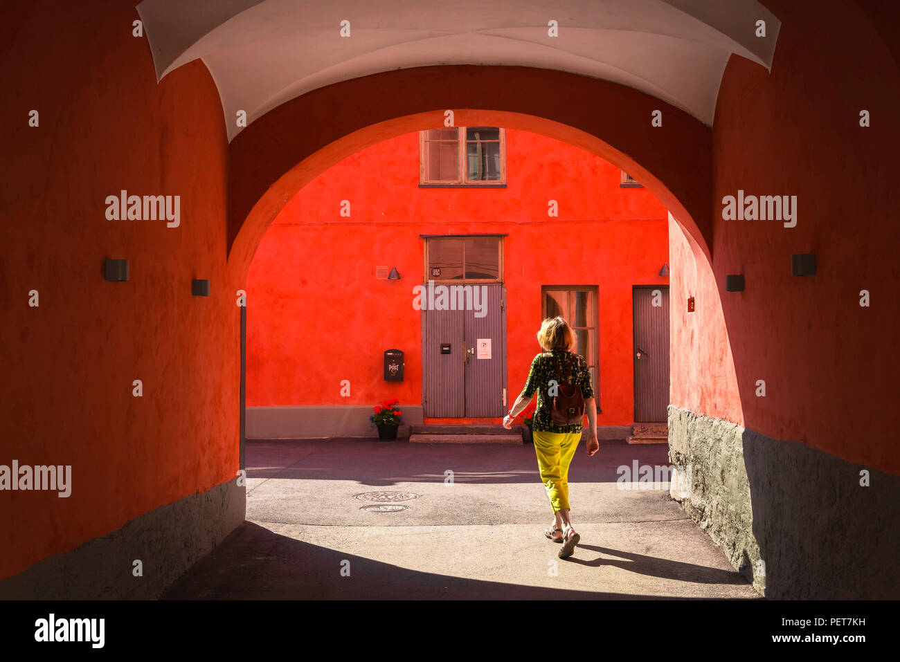 Frau solo Reisen, Rückansicht eines mittleren Alters weibliche Reisende allein durch eine farbenfrohe Arcade in der Altstadt von Helsinski, Finnland. Stockfoto