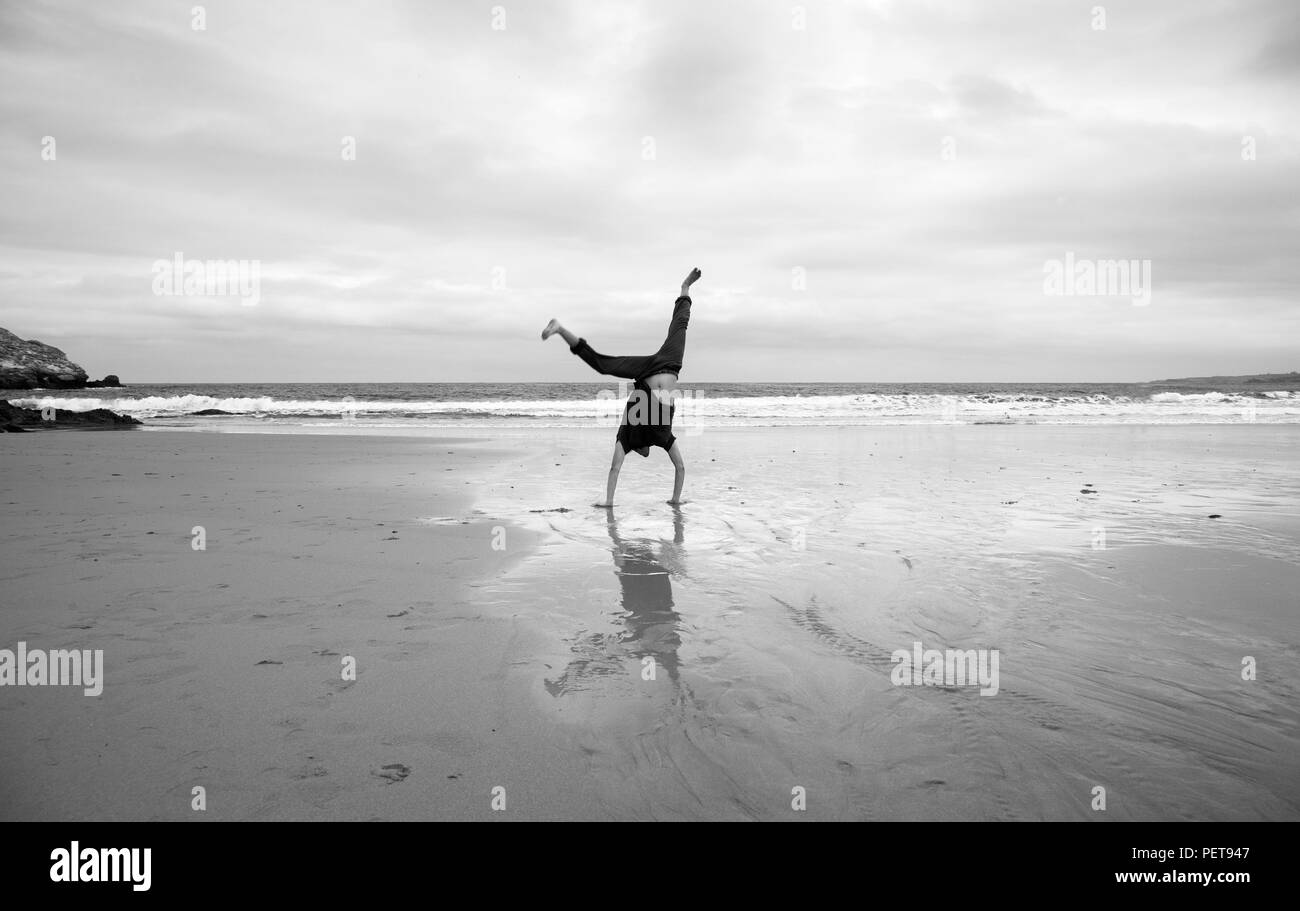 Junger Mann, Akrobatik zu tun auf einem Strand Stockfoto