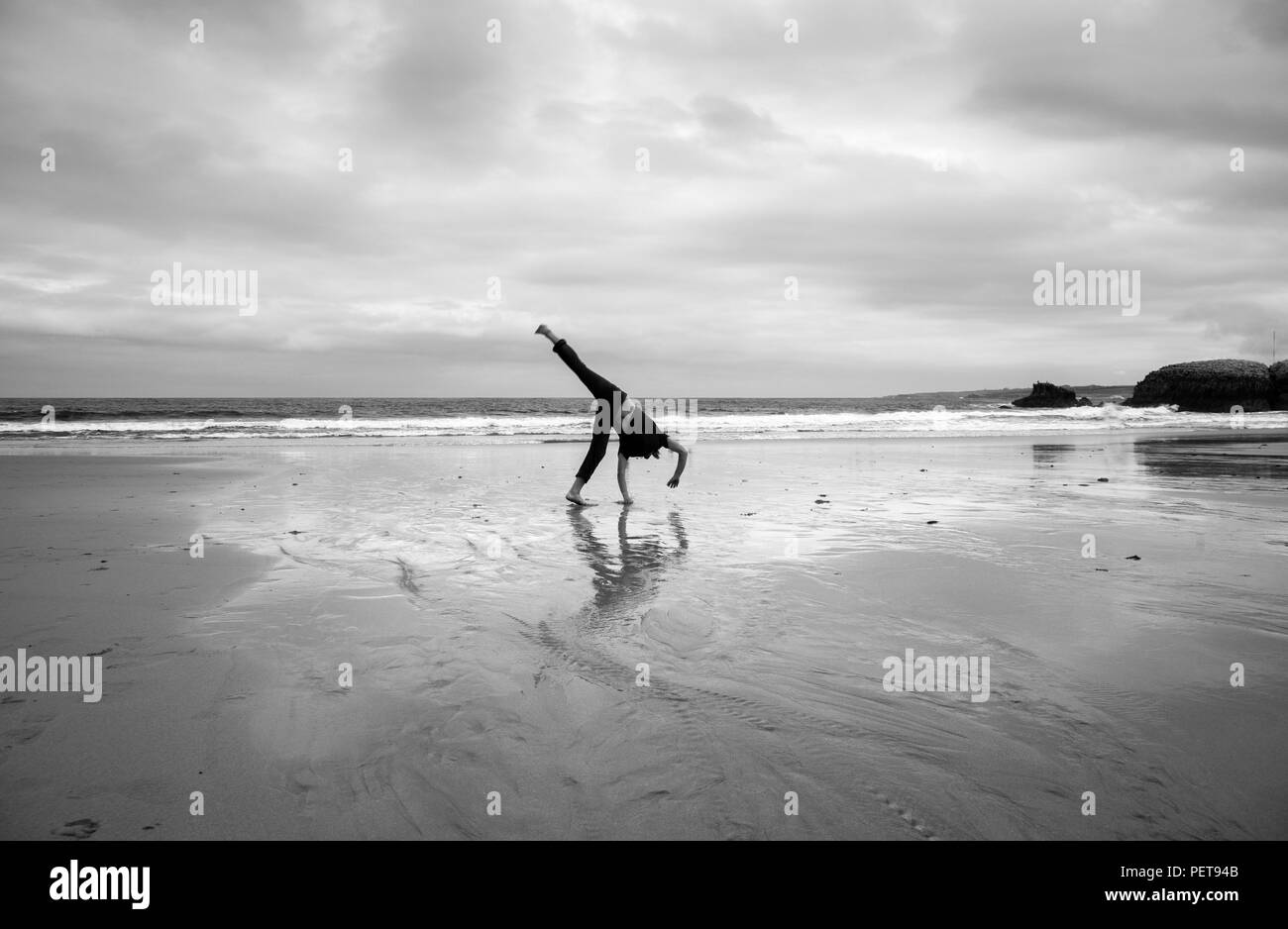 Junger Mann, Akrobatik zu tun auf einem Strand Stockfoto