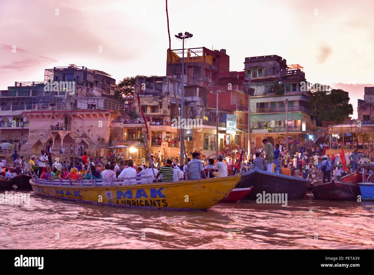 Indianer und Touristen auf Booten in Dashashwamedh Ghat am Abend auf dem Ganges-Fluss in Varanasi, Indien Stockfoto