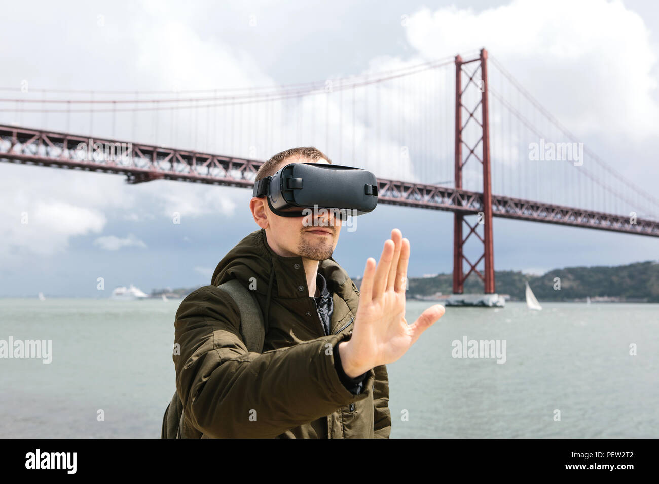 Ein Mann mit Virtual reality Brillen. Das Konzept der Virtuellen reisen. 25 April Brücke in Lissabon im Hintergrund. Das Konzept der modernen Technologien und deren Einsatz im täglichen Leben. Stockfoto