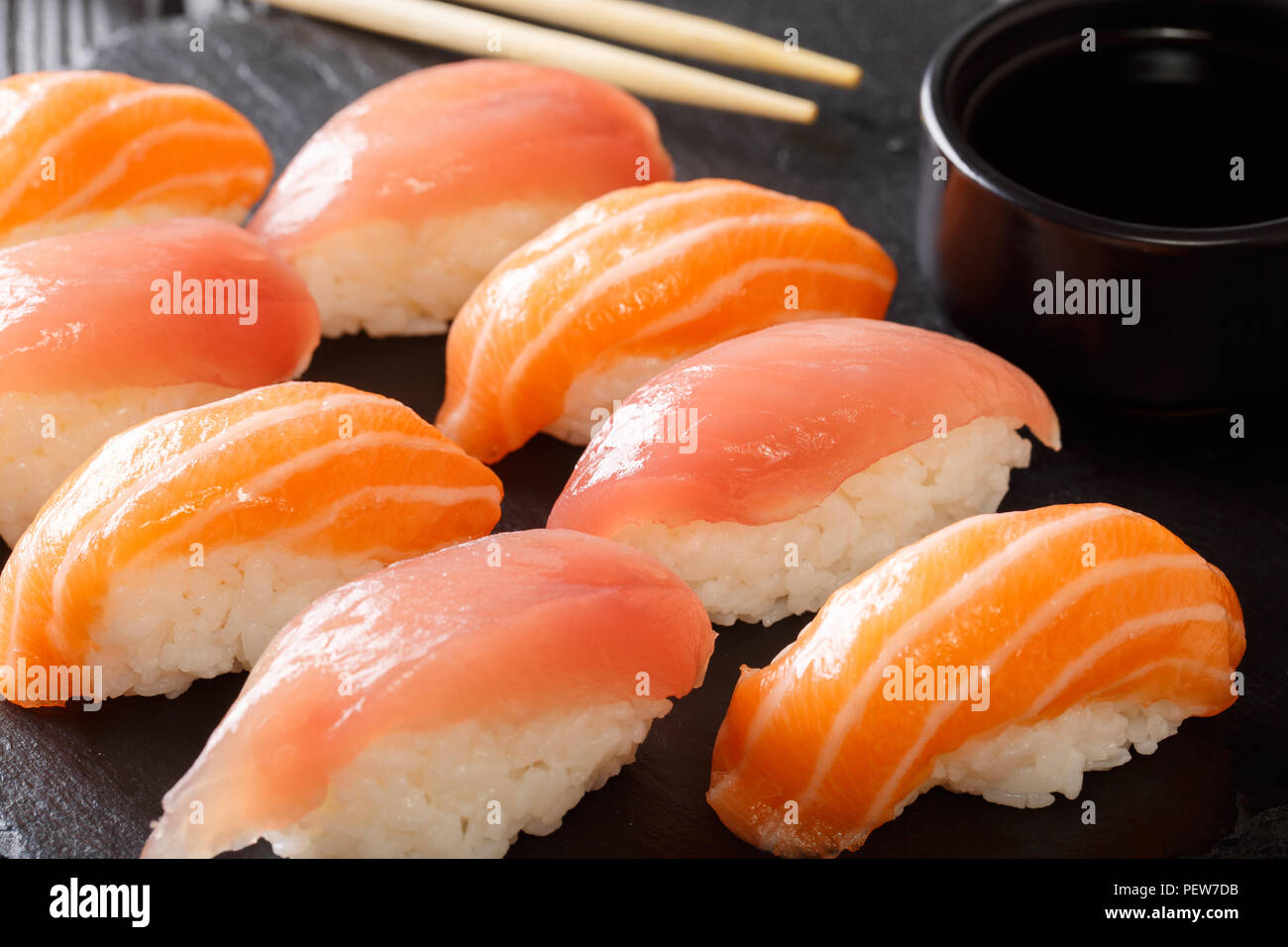 Japanisches Essen: Sushi mit Lachs und Thunfisch, Sojasoße close-up auf einem schwarzen Schiefer. Horizontale Stockfoto
