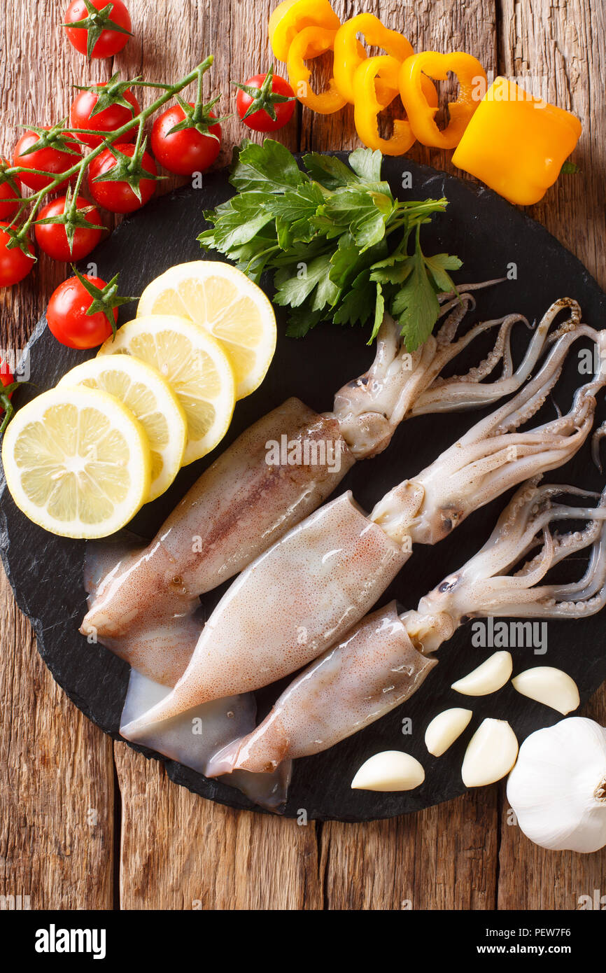 Meeresfrüchte frische Tintenfische mit Tentakeln close-up und Gemüse für die Küche auf den Tisch. Vertikal oben Ansicht von oben Stockfoto