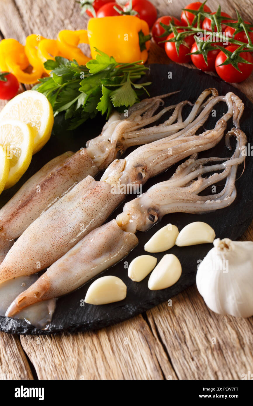 Meeresfrüchte frische Tintenfische mit Tentakeln close-up und Gemüse für die Küche auf den Tisch. Vertikale Stockfoto