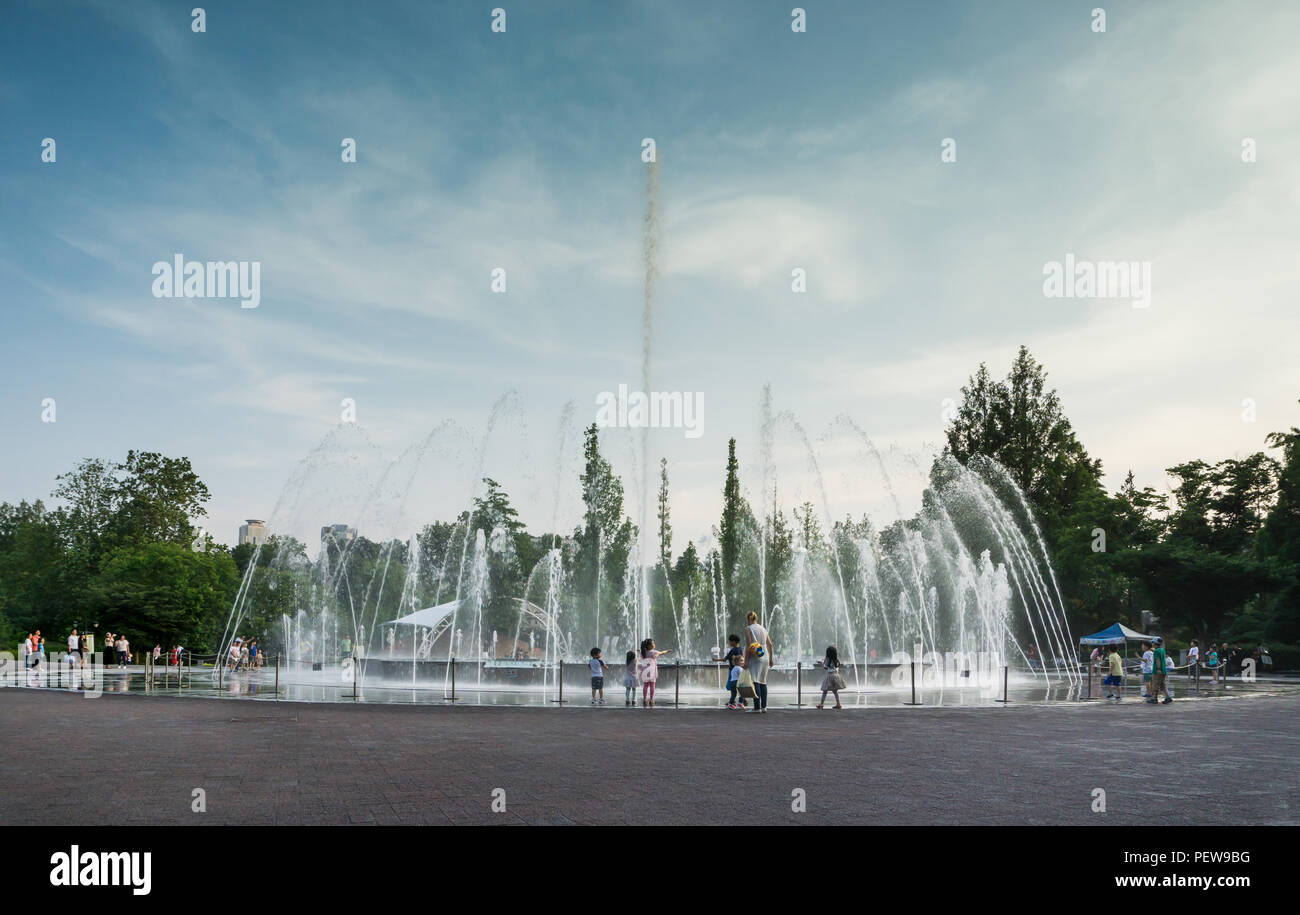 Spielende Kinder mit den Eltern in der Etage Brunnen auf dem Platz. Ein heißer Sommertag kurz vor Sonnenuntergang. Es ist Musik Brunnen. Stockfoto