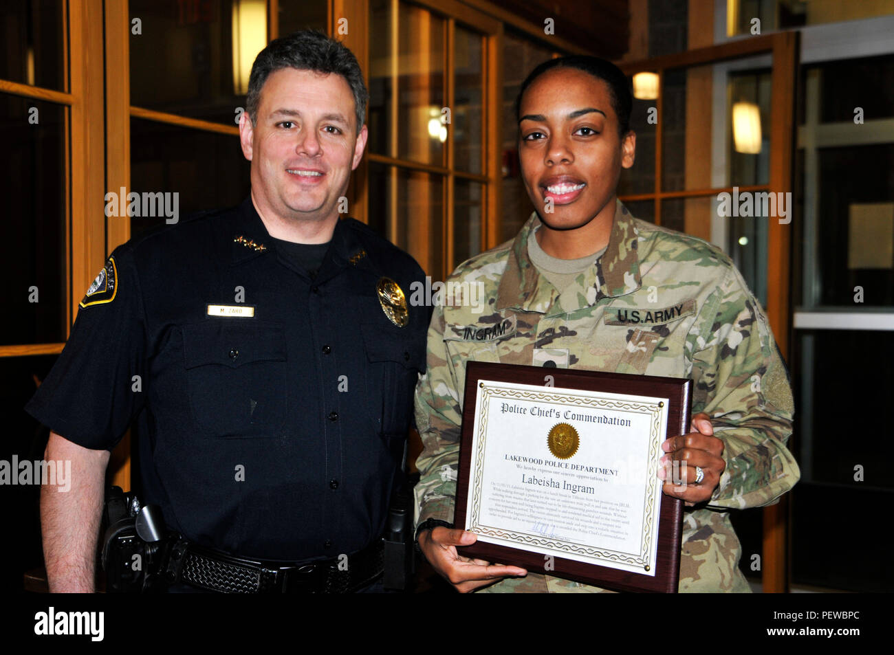 Spc. Labeisha Ingram, rechts, Field Artillery firefinder radar Operator für die Zentrale und Sitz der Batterie, 17 Field Artillery Brigade zugeordnet, 7 Infanterie Division und ein Eingeborener von Queens, New York, posiert für ein Foto mit der Polizeichef Michael Zaro, Lakewood Stadtpolizei, nach Erhalt des Chief Lob an der Lakewood Rathaus, Feb 1, 2016. Ingram erhielt die Auszeichnung für ihre Aktionen im November vergangenen Jahres, als sie ein Opfer das Leben gerettet, indem Sie ärztliche Hilfe, bis Rettungskräfte zu der Szene. Stockfoto