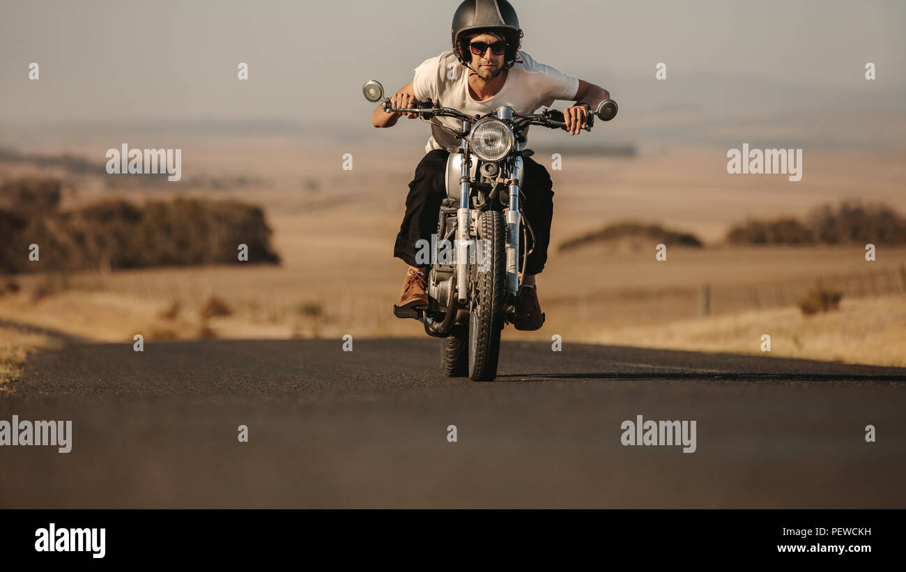 Porträt der jungen Mann, der ein Motorrad schnell auf der Autobahn. Männliche Fahrer nach vorne während der Fahrt sein Motorrad. Stockfoto