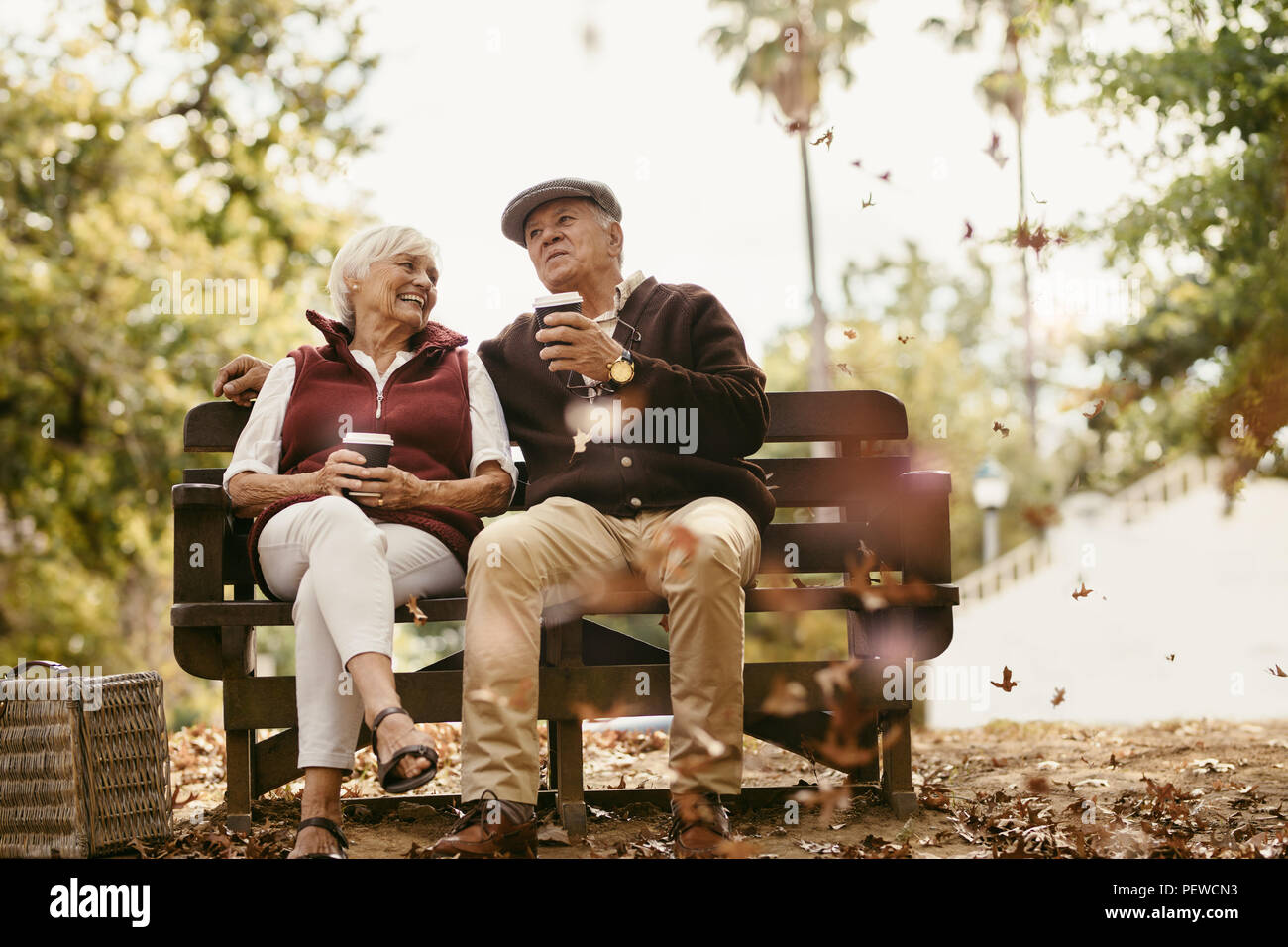 Entspannt senior Paar auf Picknick sitzen auf einer Parkbank ins Gespräch und Kaffee. Alte Mann und Frau entspannen im Park/in. Stockfoto