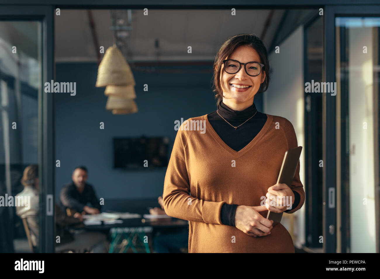 Portrait von positive weibliche Führungskräfte mit einem Laptop im Büro mit den Kollegen im Hintergrund arbeiten. Lächelnd Business woman in Casuals an Stockfoto