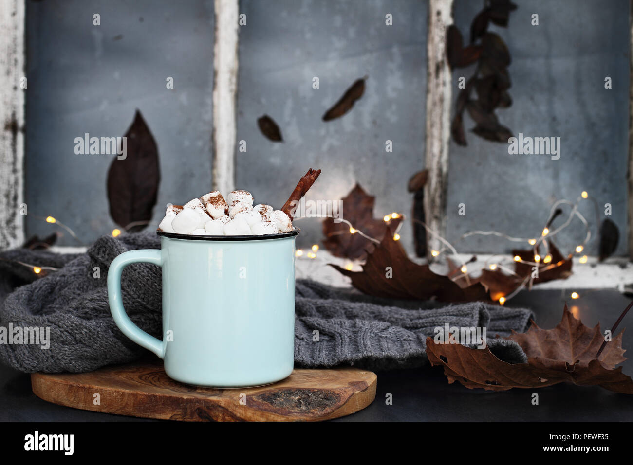 Blau und Schwarz Emaille Tasse heißen Kakao mit Marshmallows und Zimt Rinde vor einem alten Fenster. Extrem flache Tiefenschärfe mit Fokus auf dri Stockfoto