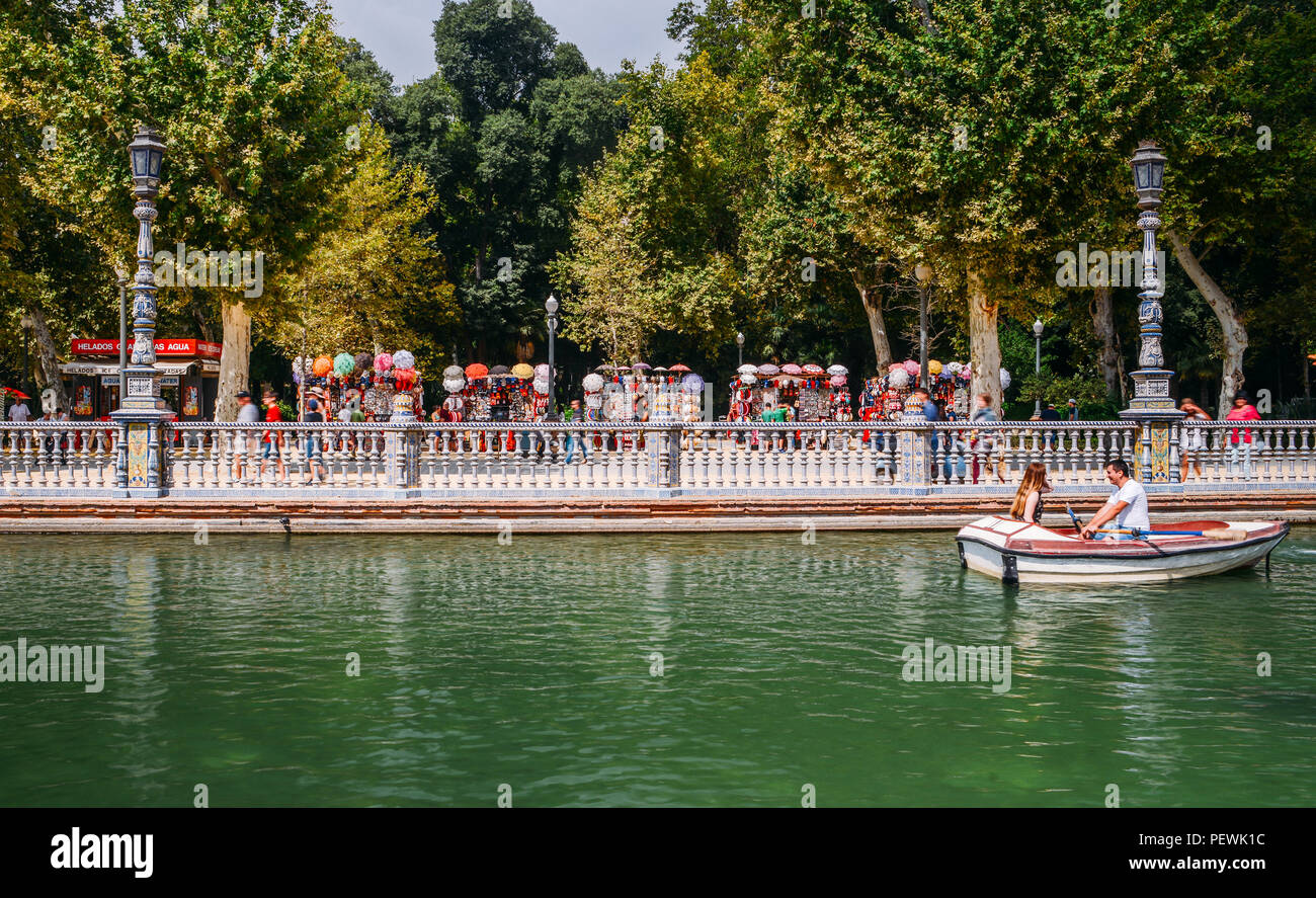 Sevilla, Spanien - 15. Juli 2018: Touristen schweben auf einem Boot auf dem Kanal spanischen Plaza de Espana mit Souvenir stand im Hintergrund Stockfoto