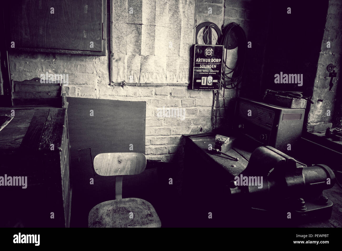 Alte Werkstatt mit Arbeitsplatz in einer Industrie Museum mit dunklen Touch und ein altes Radio in Schwarz und Weiß Stockfoto