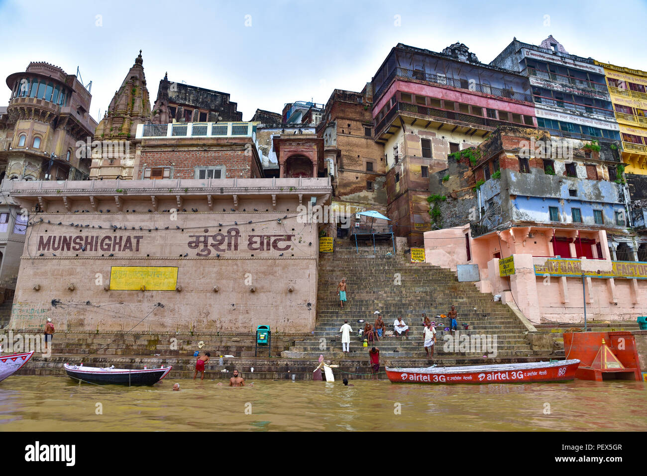 Gebäude und Ghat entlang Ganges mit Menschen und Boote Stockfoto