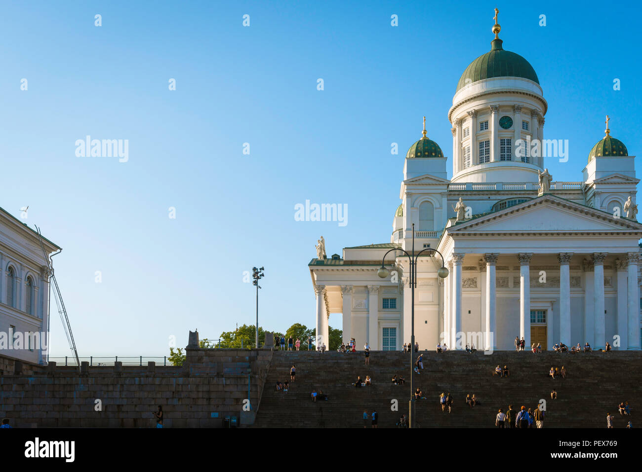 Finnland Tourismus Sommer, Aussicht bei Sonnenuntergang der lutherischen Kathedrale in Helsinki mit Touristen sitzen auf oder Aufsteigend der großen Treppe zu seinem Eingang. Stockfoto