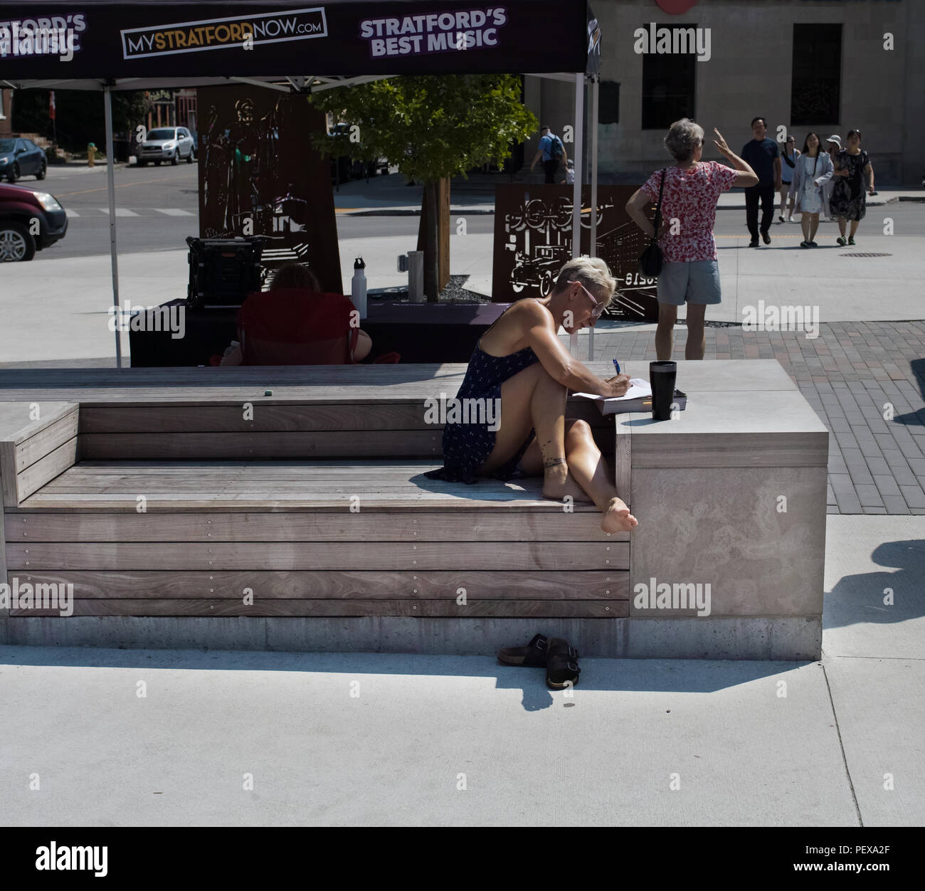Sie nimmt ein Sonnenbad, schreibt etwas auf dem Marktplatz Stockfoto