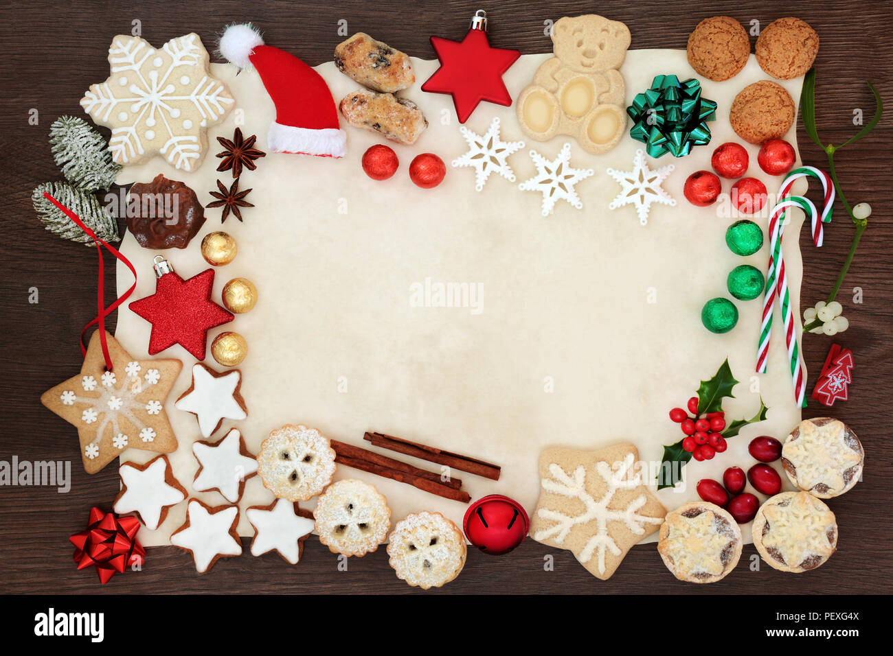 Weihnachten festliche Hintergrund Grenze einschließlich Christbaumschmuck,  Kekse, Kuchen, Schokolade, Gewürze und Winter Flora auf Pergamentpapier auf  Eiche rustikal Stockfotografie - Alamy