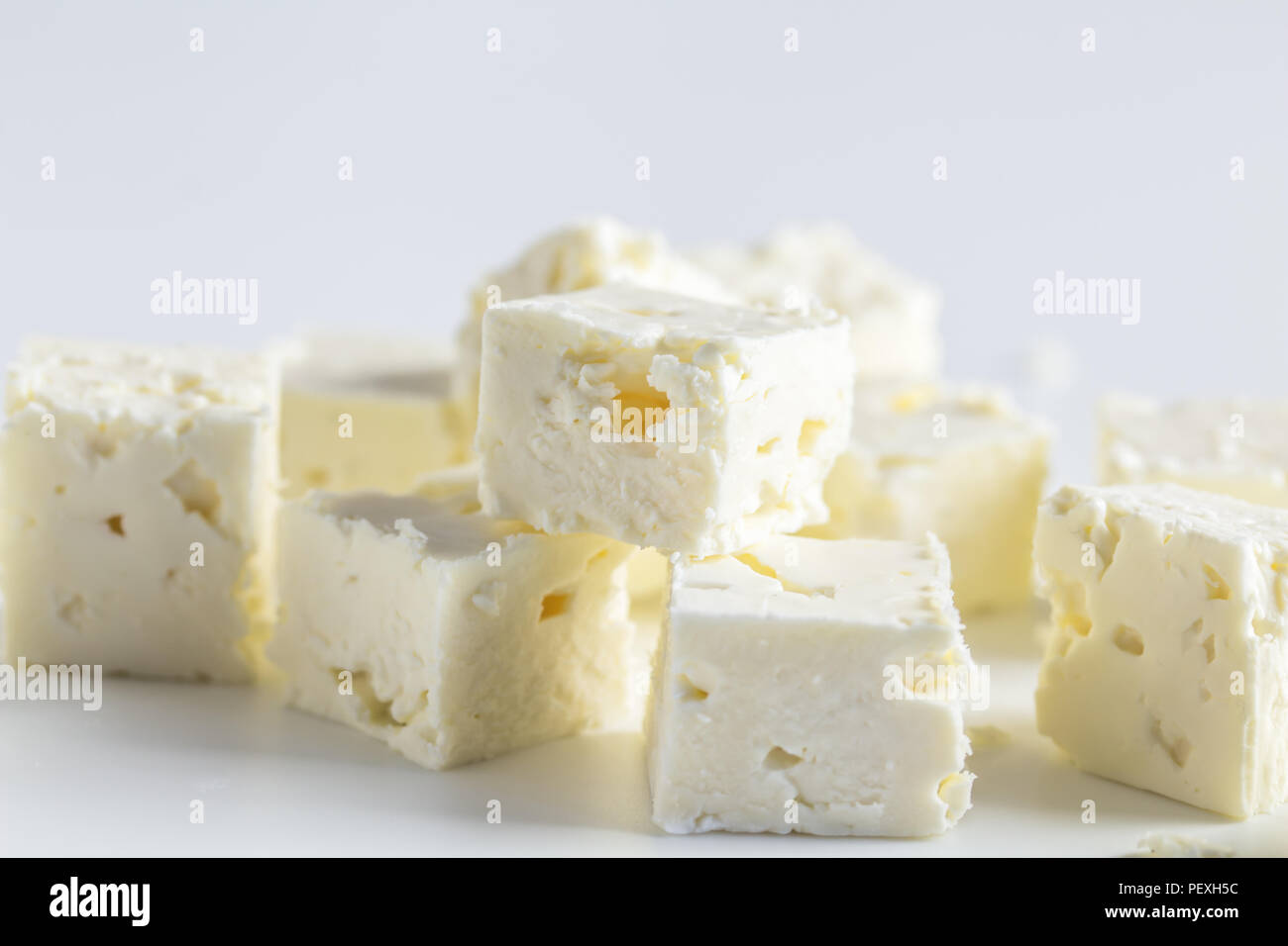 Feta Käsewürfel auf weißem Hintergrund mit selektiven Fokus isoliert Stockfoto