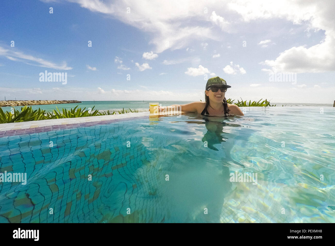 Frau schwimmen in Oceanside Pool mit Cocktailbar Stockfoto