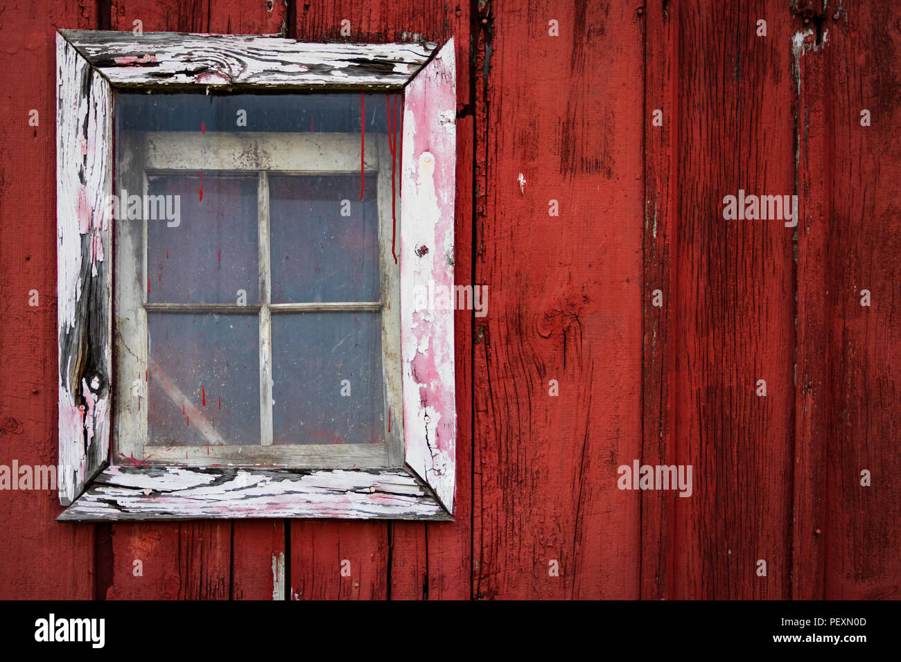 Weiß gerahmte Fenster auf einem alten roten Scheune. Stockfoto