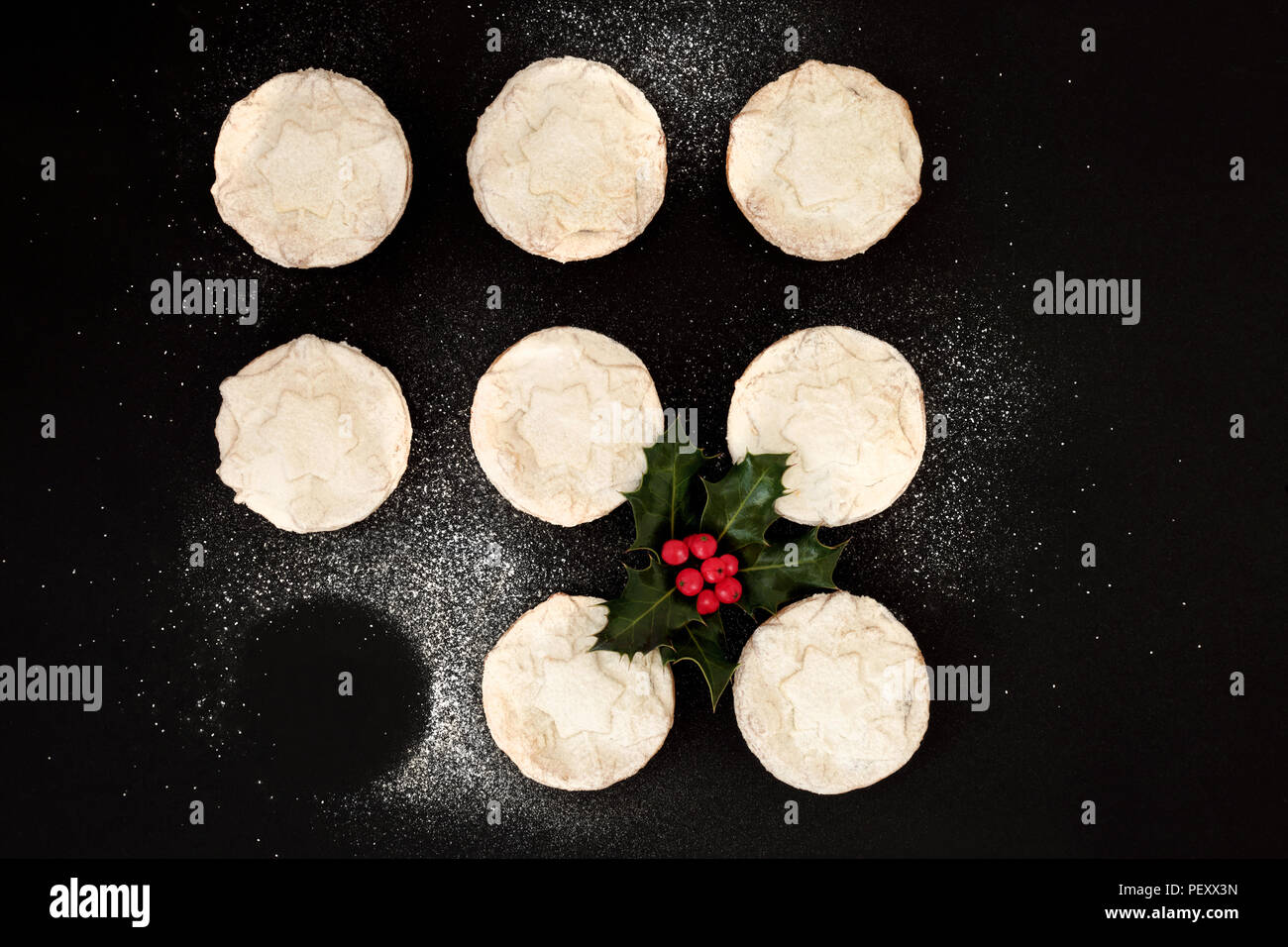 Leckere frisch gebackene Weihnachten Torten mit einem fehlenden, mit Holly Berry blatt Zweig und Puderzucker abgestaubt auf schwarzem Hintergrund vor den Mund. Ansicht von oben. Stockfoto