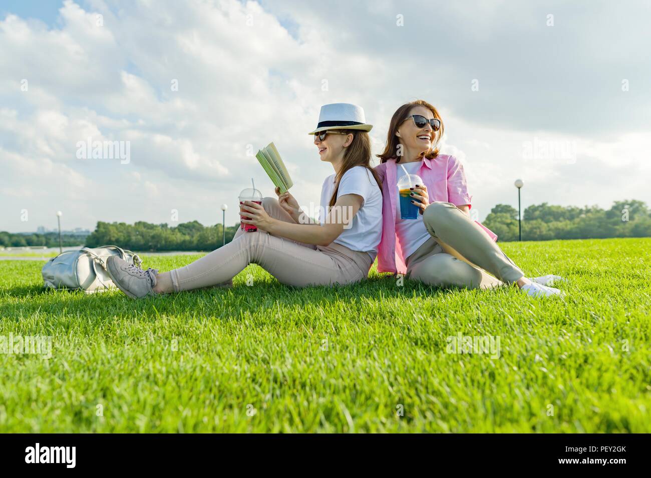 Die Kommunikation Von Eltern Und Teenager Mutter Und Tochter Auf Der Grunen Wiese Im Park Und Lesen Buch Sitzen Trinken Einen Kuhlen Cocktail Und Geniessen Stockfotografie Alamy