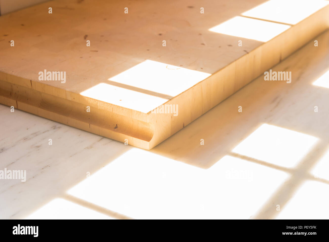 Eine Küche aus Holz Schneidbrett auf der Arbeitsplatte in der Küche, mit einem Fenster, das Sonnenlicht auf Sie. Stockfoto Eine Küche aus Holz Schneidbrett auf der Arbeitsplatte in der Küche, mit einem Fenster, das Sonnenlicht auf Sie. Stockfoto