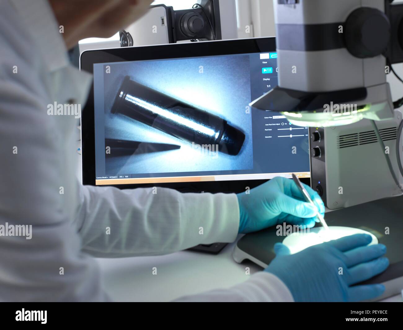 Forensische Wissenschaftler mit Hilfe einer 3-D Stereo Mikroskop Markierungen auf einer Kugel in das Labor während einer strafrechtlichen Untersuchung zu sehen. Stockfoto
