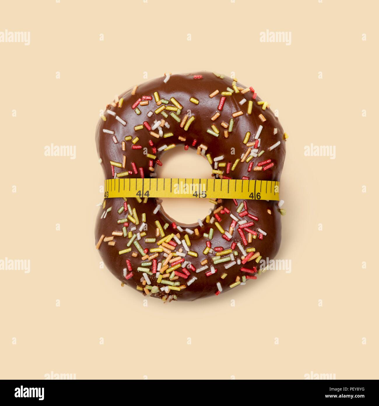 Das Nähren, konzeptionelle Bild. Schokolade Donut mit Zucker Litzen und Maßband, Studio gedreht. Stockfoto