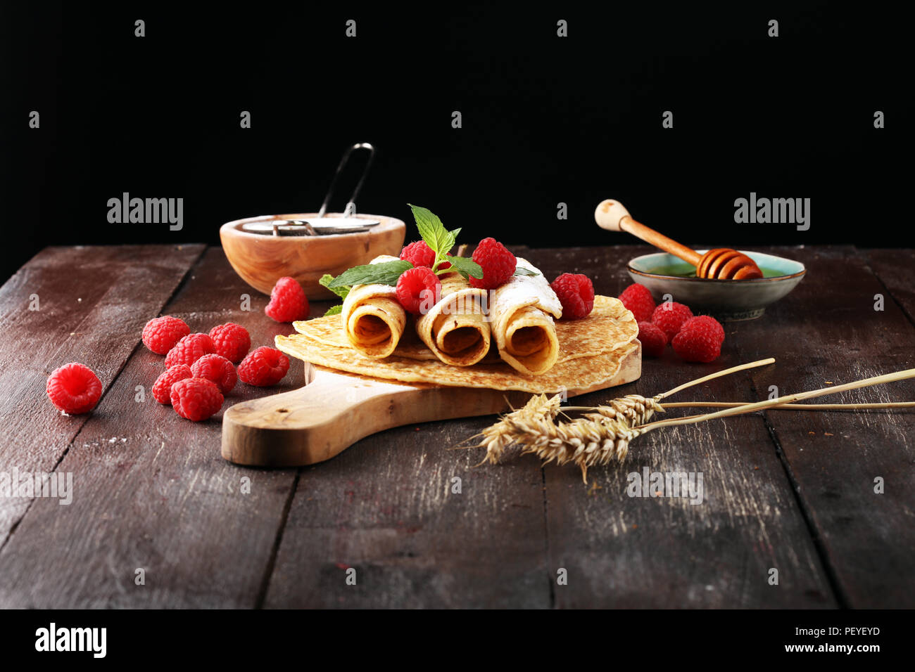 Hausgemachte crepes serviert mit frischem raspberrries und Puderzucker auf rustikalen Tisch Stockfoto
