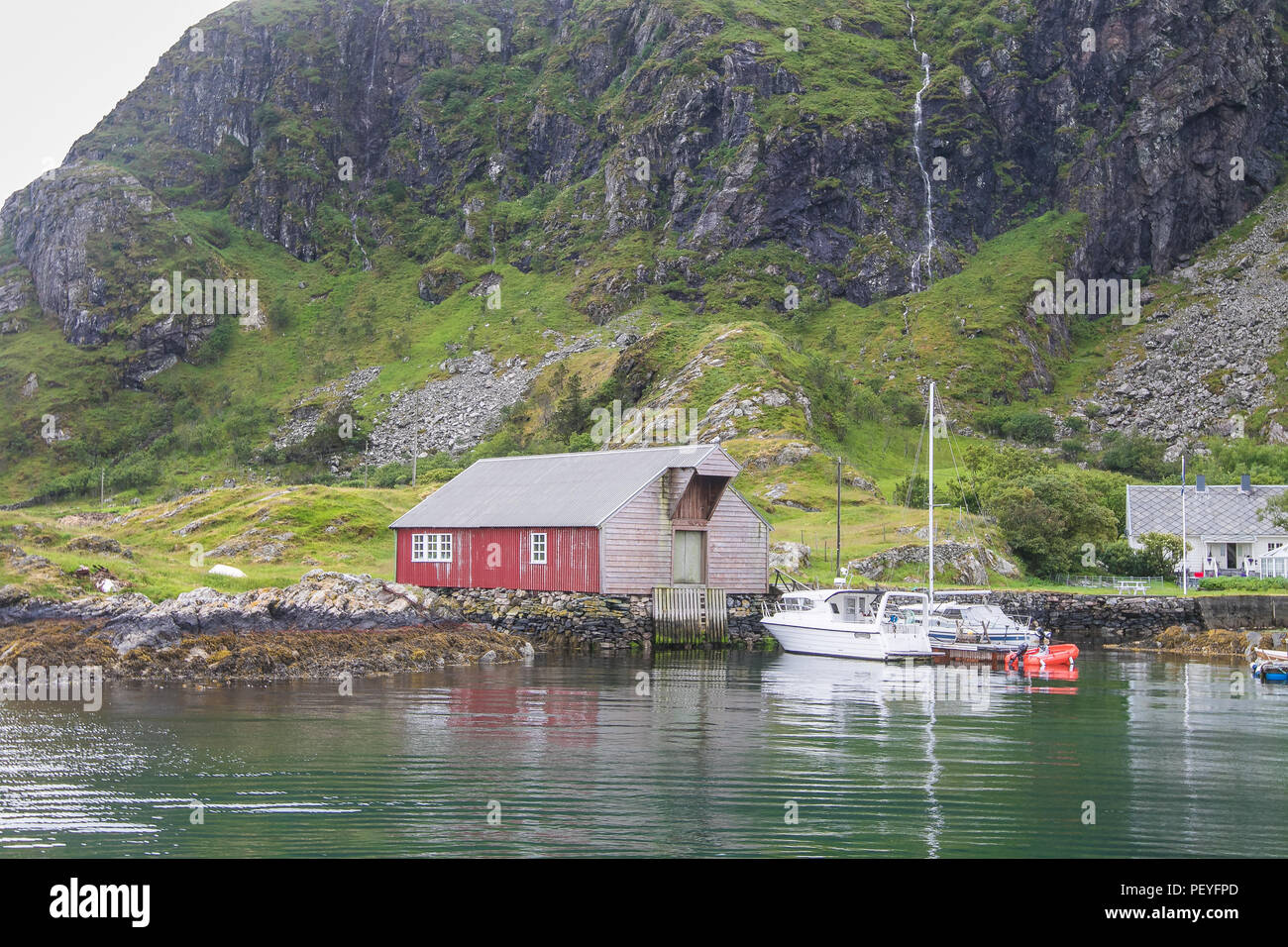 Haus in der Nähe von Water Edge mit angedockten Boote auf einer kleinen norwegischen Insel. Stockfoto