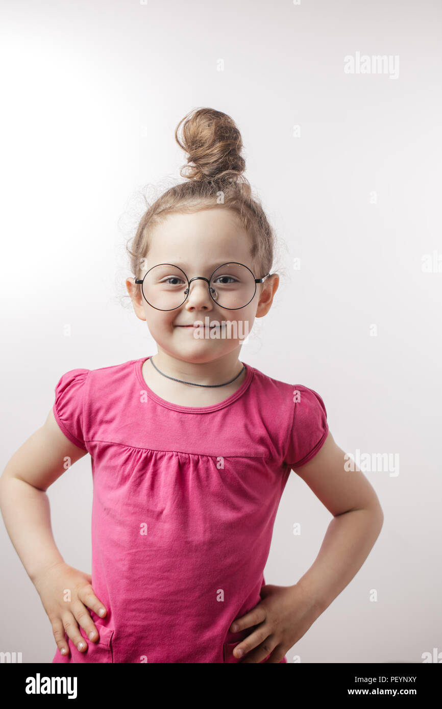 Positive lächelnde Mädchen mit hairbun tragen stilvoll trendy Kleid, runde Gläser und Kette. Kindheit Konzept Stockfoto