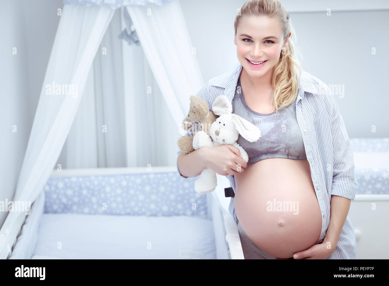 Schwangere Frau zu Hause niedlich, die zukünftige Mutter mit Zärtlichkeit berührt ihr Bauch, genießt die Vorbereitung ein Kinderzimmer für Ihr Baby, glückliche Mutterschaft con Stockfoto