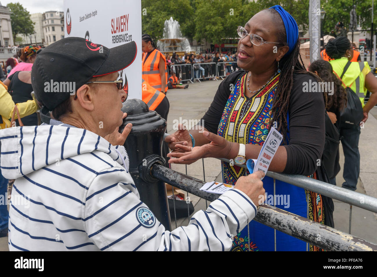 London, Großbritannien. 18. August 2018. Frauen sprechen miteinander bei der jährlichen Nationalen Gedenkfeier auf dem Trafalgar Square erinnert und ehrt die Opfer des afrikanischen Holocaust/transatlantischen Sklavenhandel und Sklaverei gefördert Internationaler Tag der Erinnerung, 23.August. Die Veranstaltung namens für die Afrikaner ihre Identität zu feiern und ihre Vorfahren zu erinnern, und begann mit Drinks erinnern viele schwarze Helden. Ers über die Diskriminierung in der Gutschrift gesprochen: Peter Marschall/Alamy leben Nachrichten Stockfoto