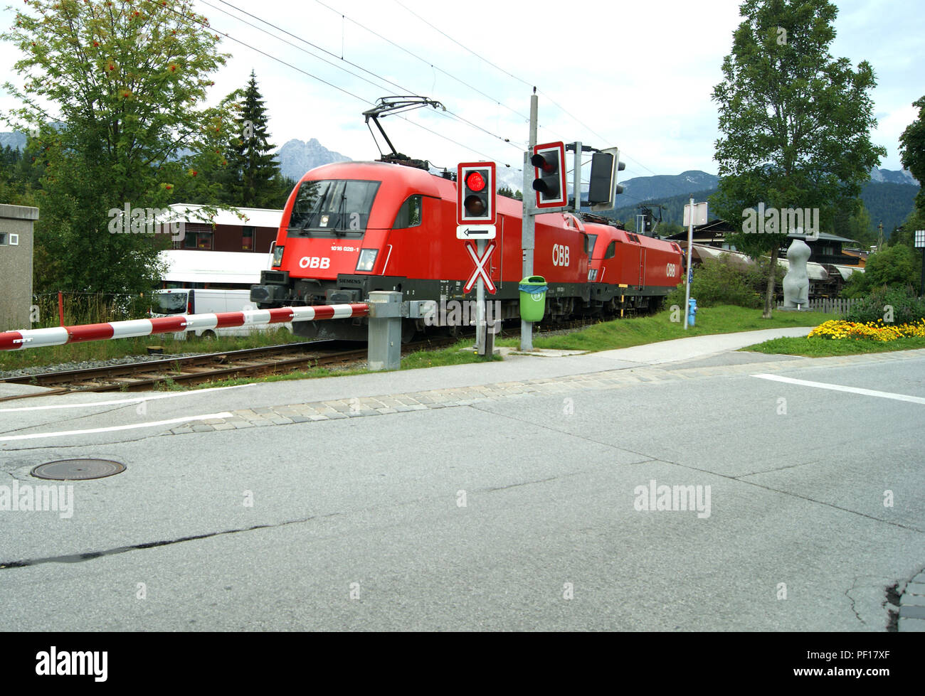 OBB 1016-028-1 Lokomotive führt andere ihrer Klasse über einen Bahnübergang in Seefeld mit einer Fracht trailn Stockfoto