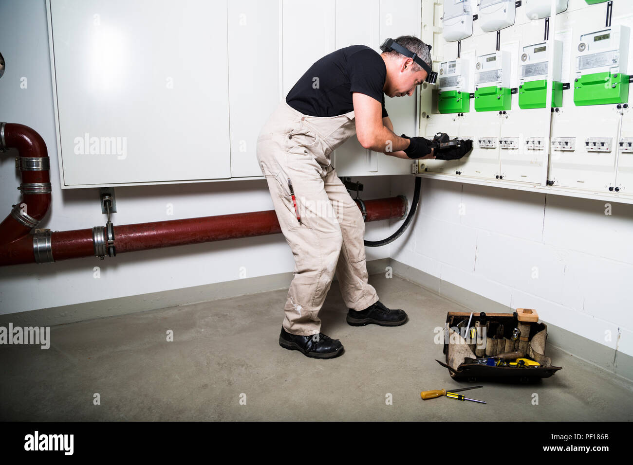 Elektriker mit Box von Tools testen Sicherungskasten oder Switch Box mit Messgerät Stockfoto