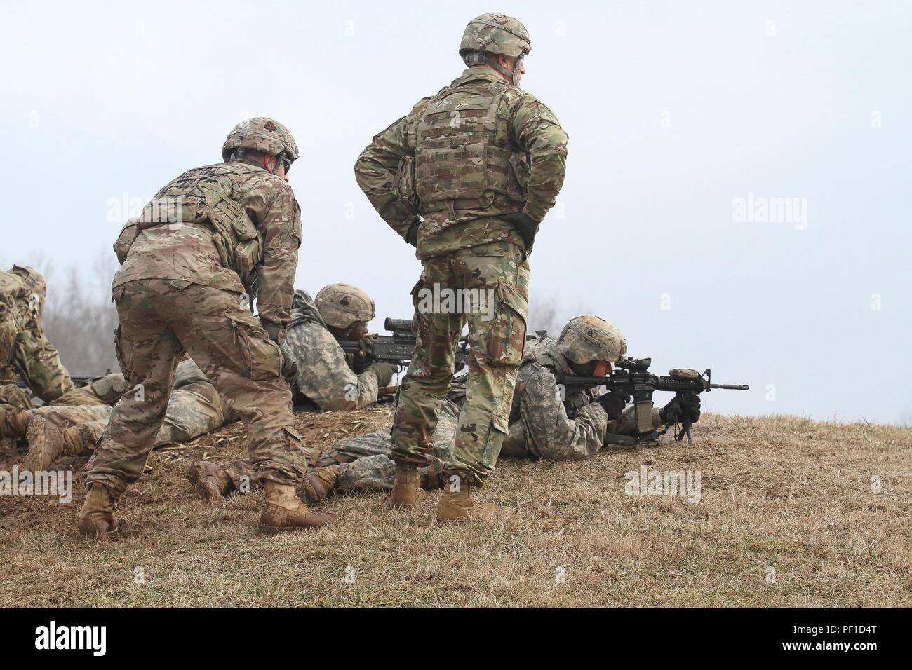 Ein noncommissioned Officer mit 1St Battalion, 506Th Infanterie Regiment "Rote Currahee", 1st Brigade Combat Team, Luftlandedivision (Air Assault), Links, lehnt sich über mehrere Soldaten mit Unternehmen C, 1.BATAILLON, 327 Infanterie Regiment "Bulldogs", während der Befehl Sgt. Maj. Scott C. Schroeder, command Sergeant Major für die US-Armee den Befehl, Recht, Uhren während eines live-fire Übung Feb.17, 2016, Reihe 55, Fort Campbell, Ky. Die Bulldog Soldaten wurden die unterstützungsfeuer, während ein weiterer Trupp durch einen Graben manövriert ihr Ziel zu erfüllen. Nach der Übung, Re Stockfoto