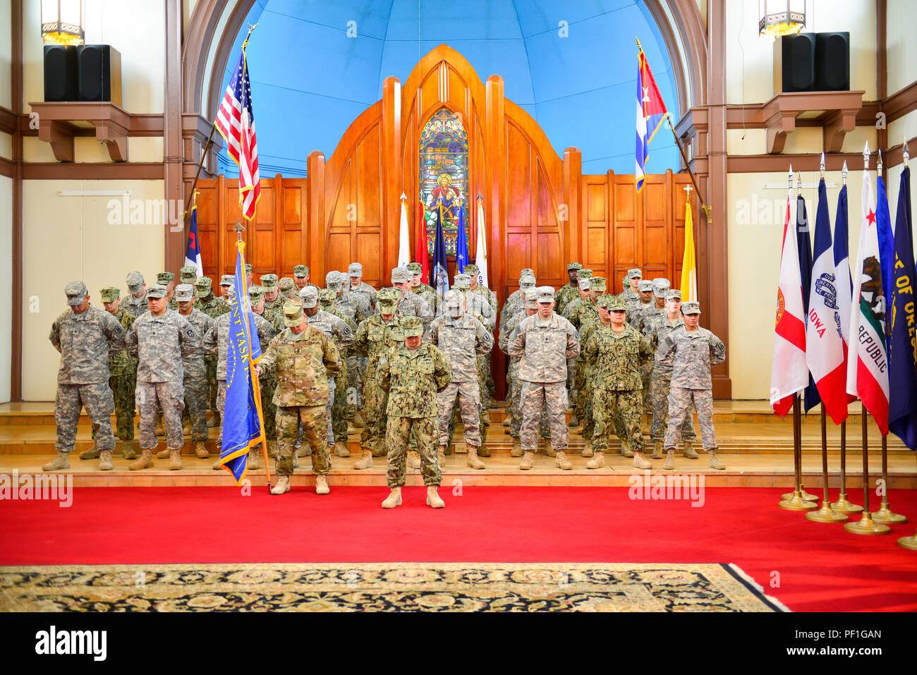 Die Bildung von troopers vom JTF, durch Army Command Sgt. Maj Carr und Marine Kapitän Bakkegard stand respektvoll während der Segnung am Ändern des Befehls Zeremonie für Marine hinten Adm. Clarke. Clarke übernahm für Brig. Gen. Jose R. Monteagudo, wie der Joint Task Force Guantanamo commander Nov. 4, 2015. (Foto durch Armee Sgt. Charlie Helmholt) Stockfoto