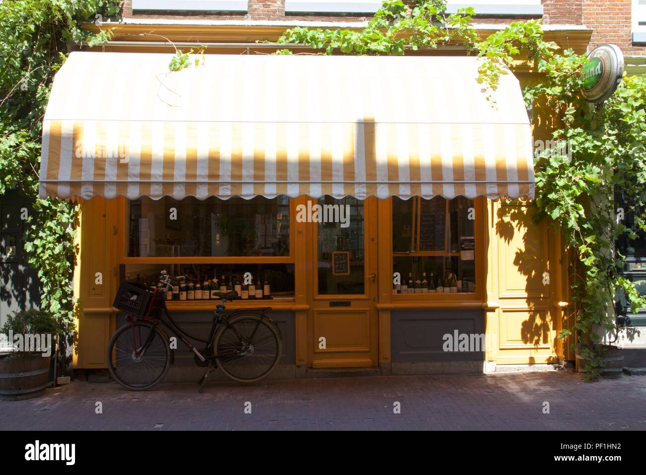 Eine kleine Vinothek mit einem gelben shopfront und ein Fahrrad geparkt außerhalb in Amsterdam, Niederlande Stockfoto