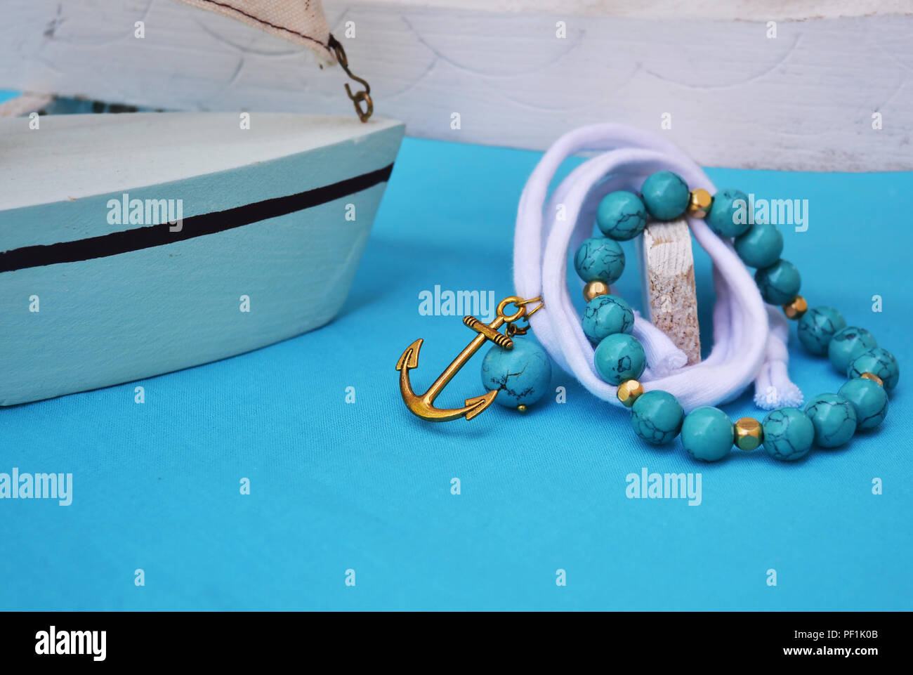 Türkis Schmuck - Schmuck mit gold Anker - türkis Hintergrund Stockfoto
