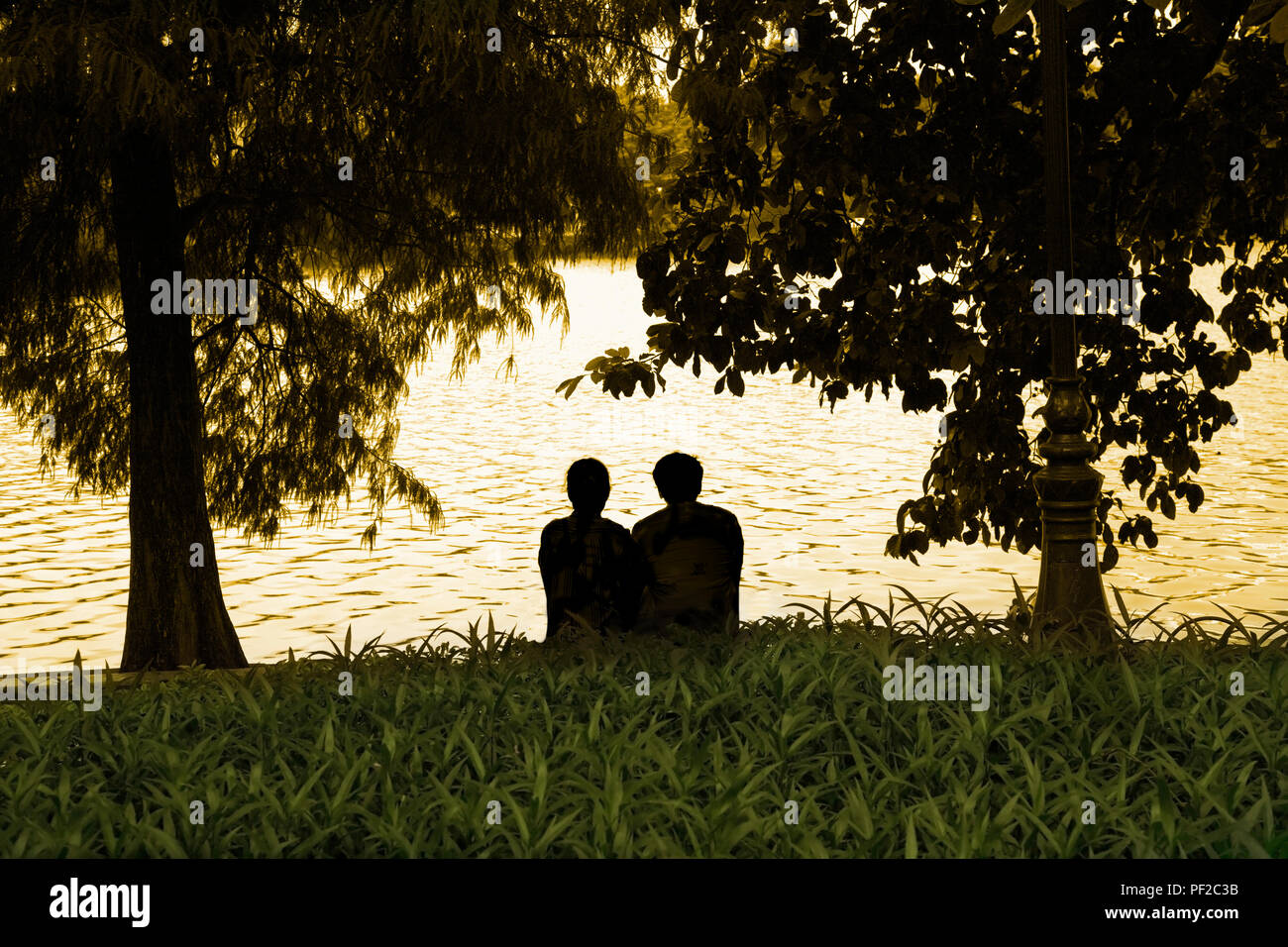 Ein paar, Liebhaber, ein Mann und eine Frau nebeneinander am Ufer sitzen. Stockfoto