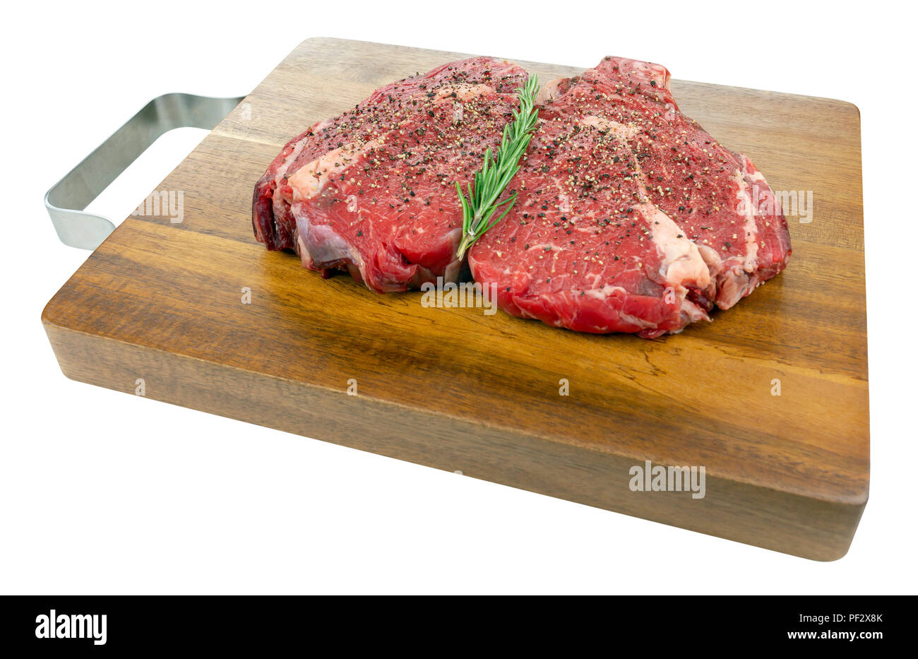 Gepfeffert raw Rib Eye Steaks mit Rosmarin auf einem hölzernen Schneidebrett in einem isolierten weißen Hintergrund Stockfoto