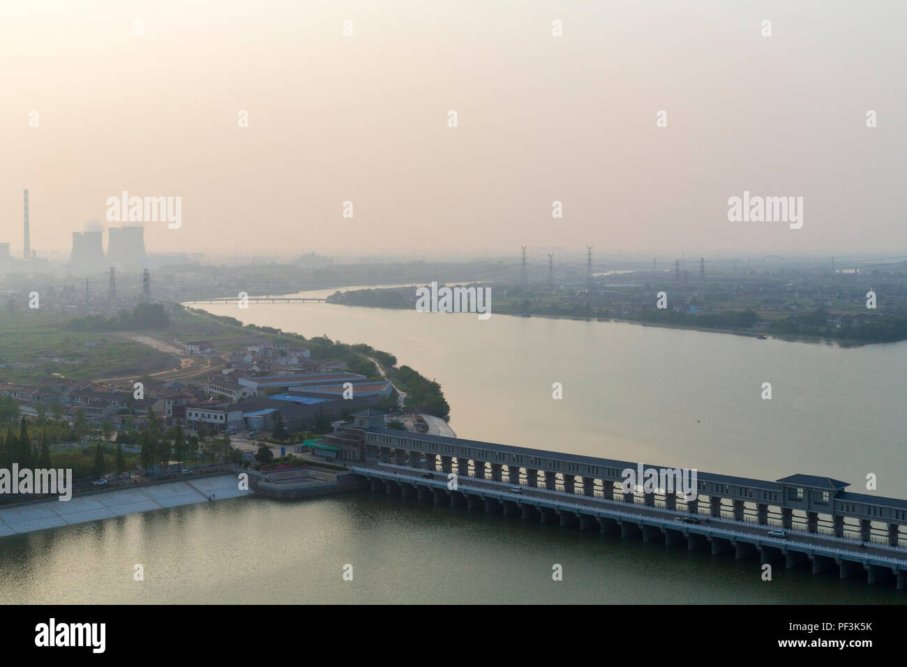 Yangzhou, Jiangsu, China. Brücke über den Fluss Liao Jia Gou. Industrielle Dunst in der Ferne, am späten Nachmittag. Stockfoto