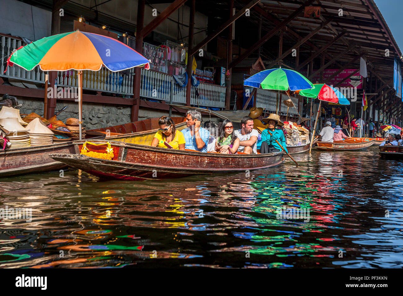 Touristen Schwimmer in einem Boot auf dem schwimmenden Markt in Thailand. damnoen, Thailand, Nov. 22, 2014. Touristische in einem Boot mit Farbe reflecitons auf dem Wasser. Stockfoto