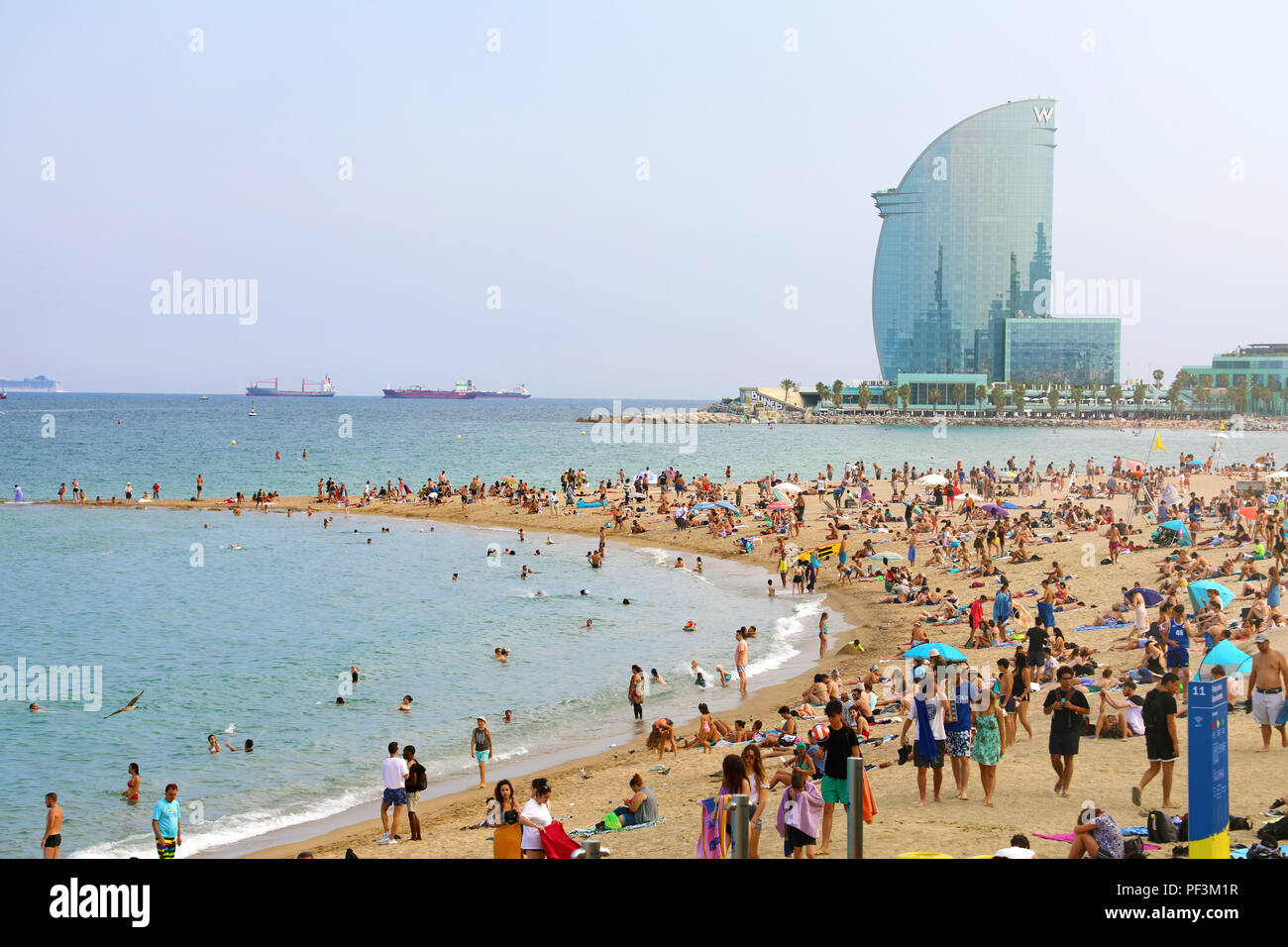 BARCELONA, SPANIEN - 11. JULI 2018: herrliche Aussicht auf den Strand von Barceloneta mit Menschen in sonniger Tag in Barcelona und W Hotel auf einem Hintergrund Catalon Stockfoto